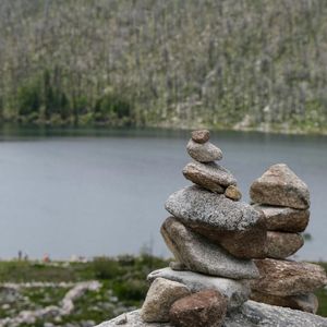 Smooth stones stacked by a calm body of water.